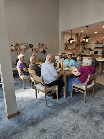 A group of elderly people are sitting around a table in a room.